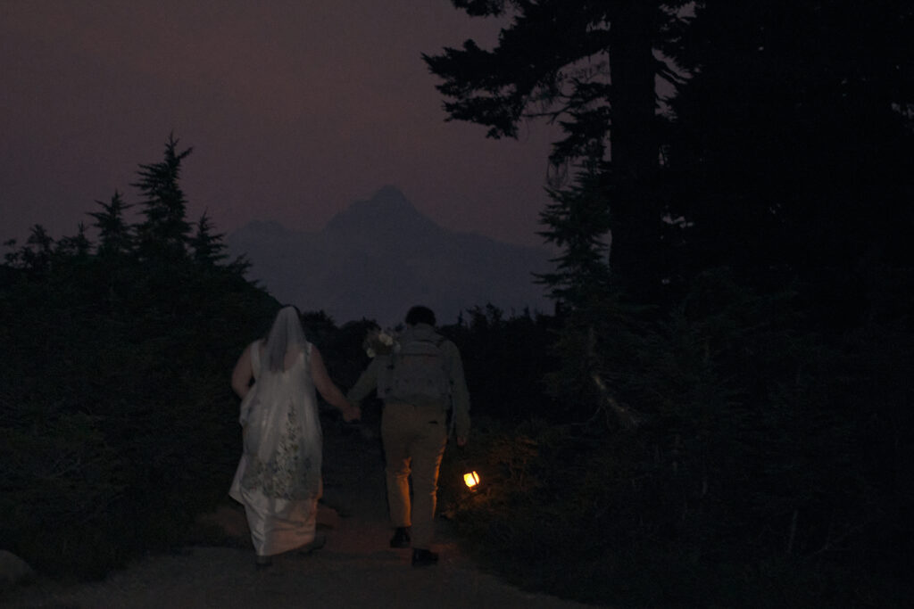 an eloping couple holds hands as they hike to their elopement spot before sunrise