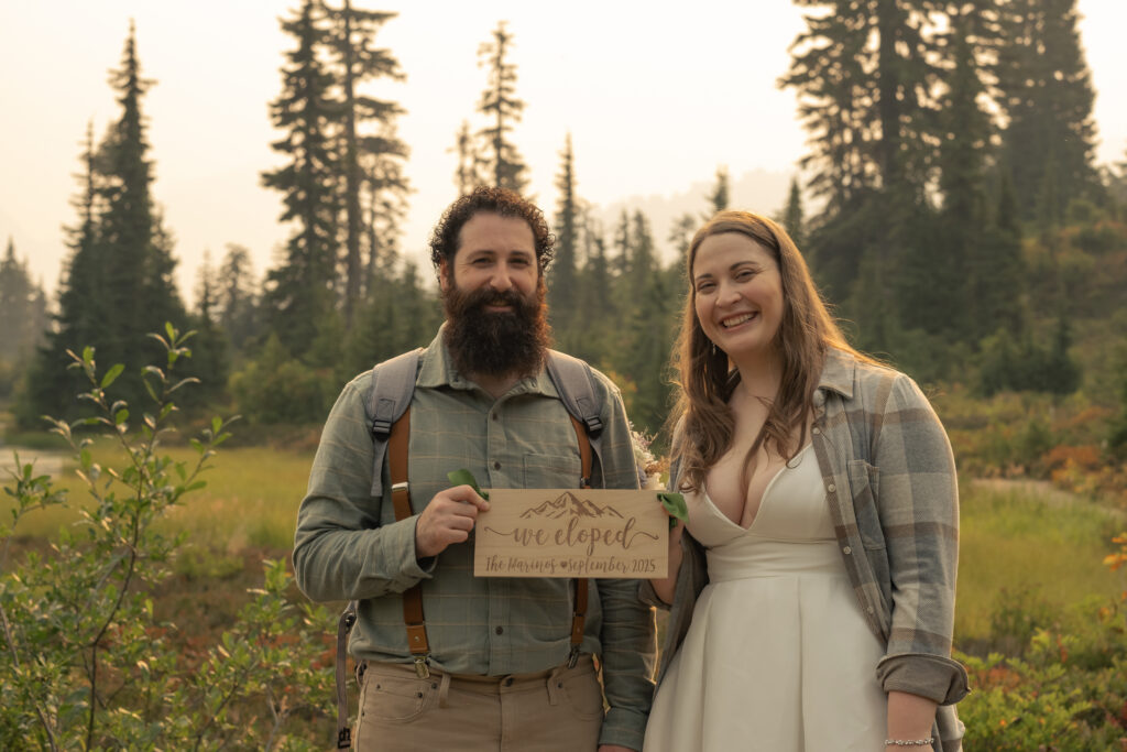 bride and groom hold a "we eloped" sign