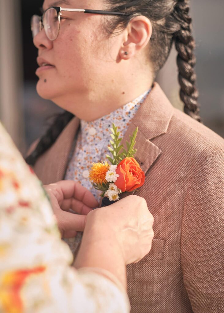 a bride pins a boutonniere on her bride