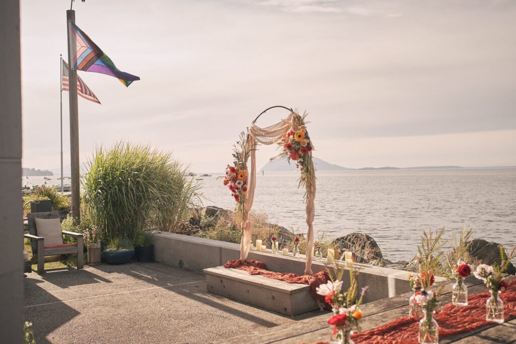 floral arch in front of the bay with distant mountains in the background