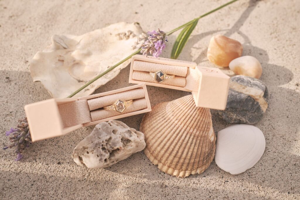 two bridal rings surrounded by seashells and wildflowers