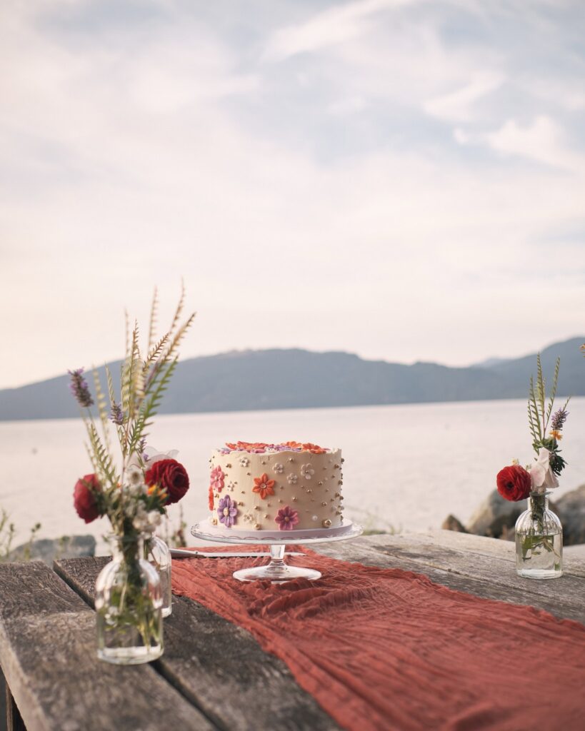 cake with floral patterns in front of the bay and distant mountains in the background