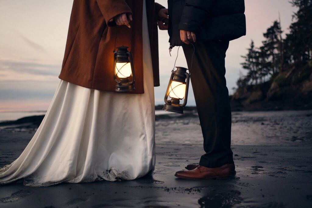 bride and groom explore the beach with lanterns after sunset