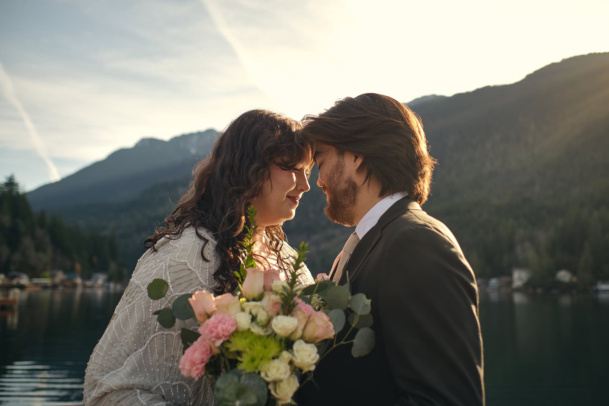 a bride and groom snuggle on a doc with their flowers